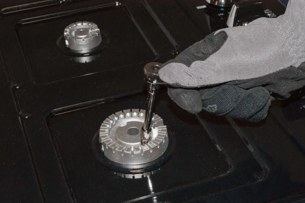 تصليح الطباخات في الكويت – فني يقوم بصيانة عيون الغاز باستخدام أدوات مخصصة