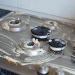Close-up of dirty gas cooker covered with chemical washing liquid. Housework or household chores concept.